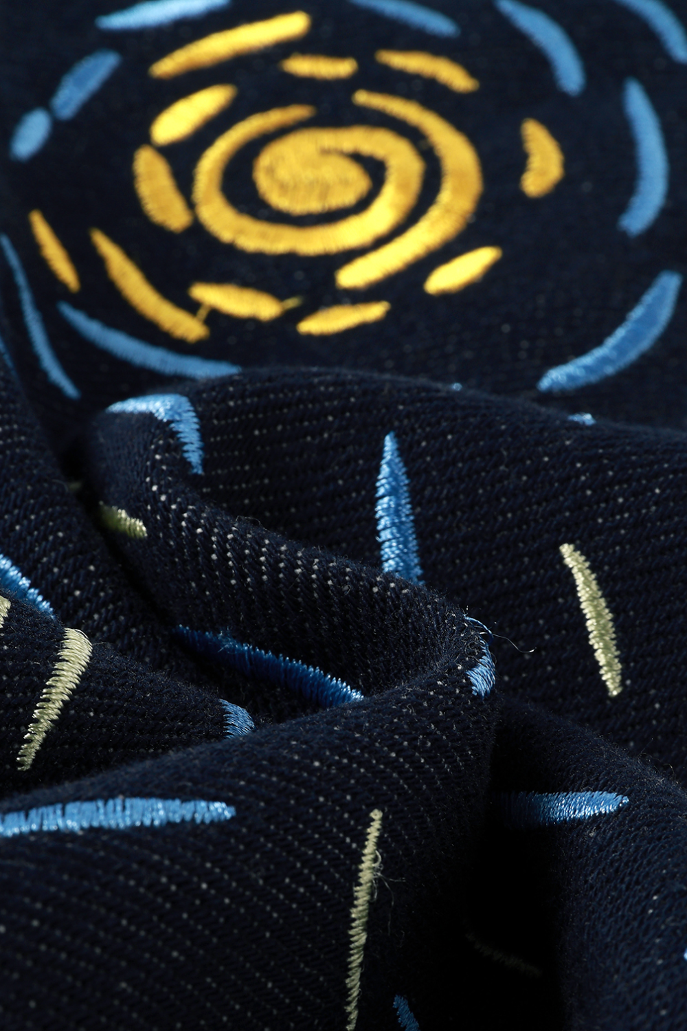 Close-up of embroidered fabric with a spiral pattern on a dark background