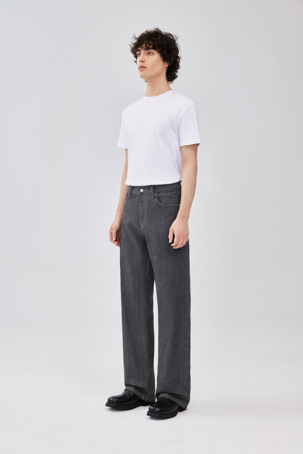 Side-front view of grey herringbone selvedge straight-leg denim jeans on a model.