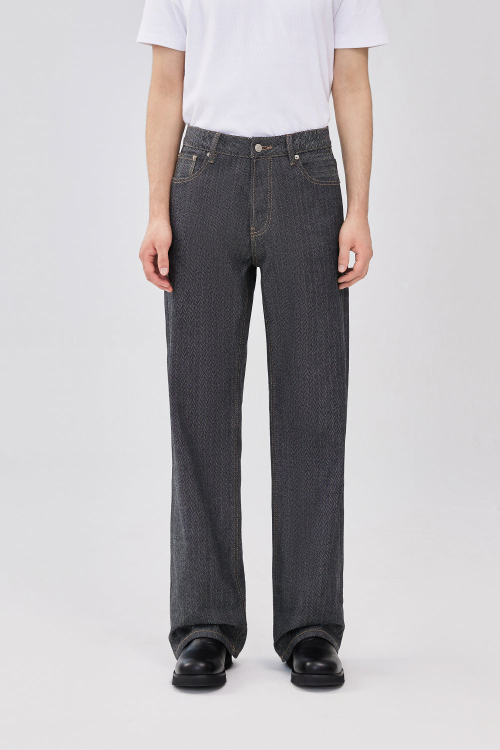 Model wearing grey herringbone selvedge straight-leg denim jeans.