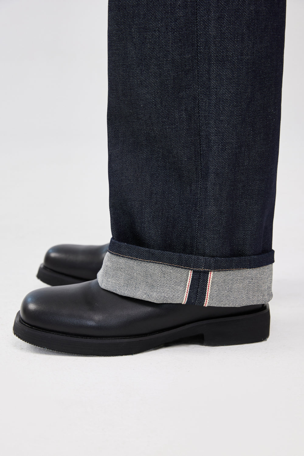 Close-up of indigo blue selvedge denim jeans with rolled cuffs showing the selvedge edge.