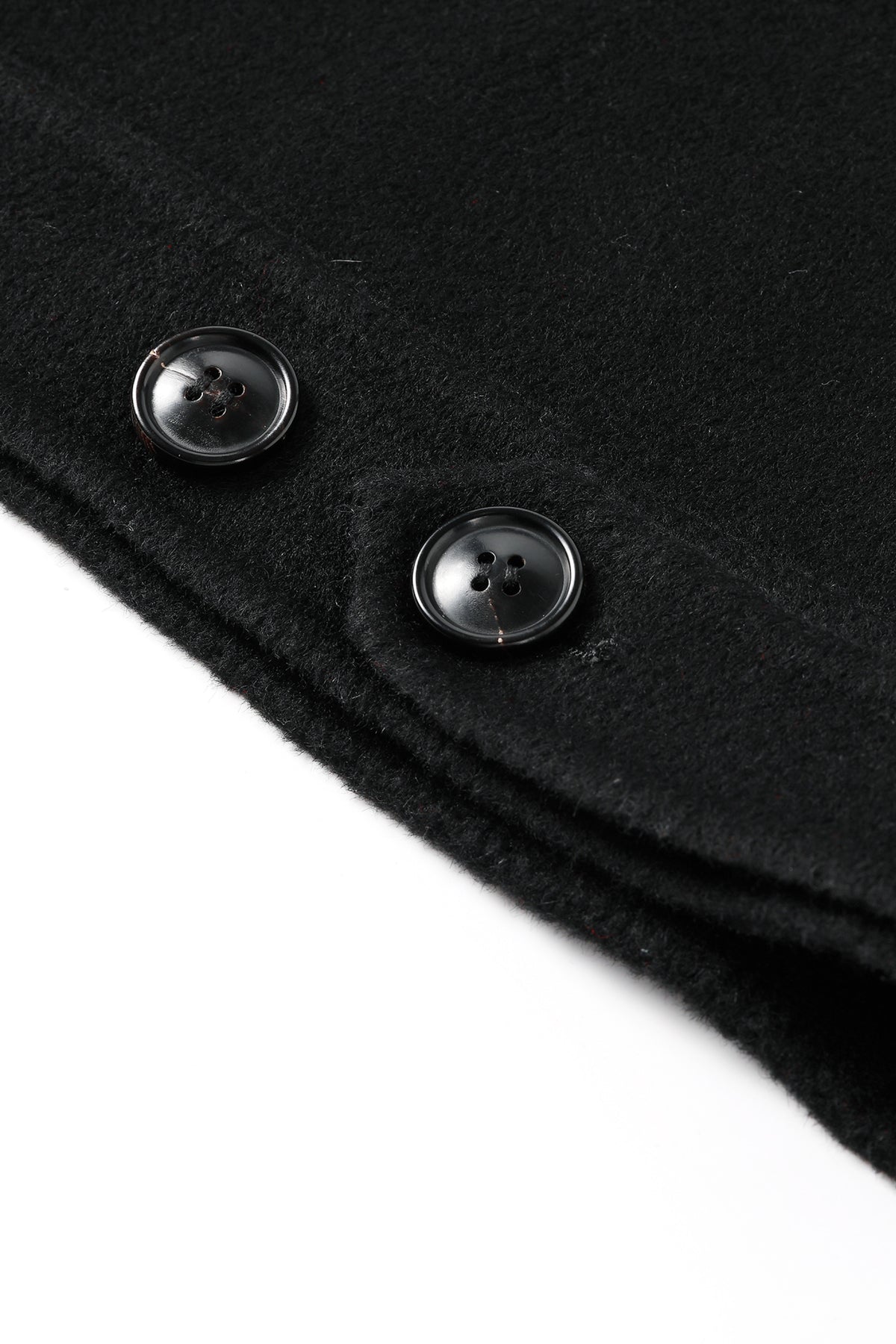 Close-up of a black wool or cashmere fabric with two black buttons on a white background.